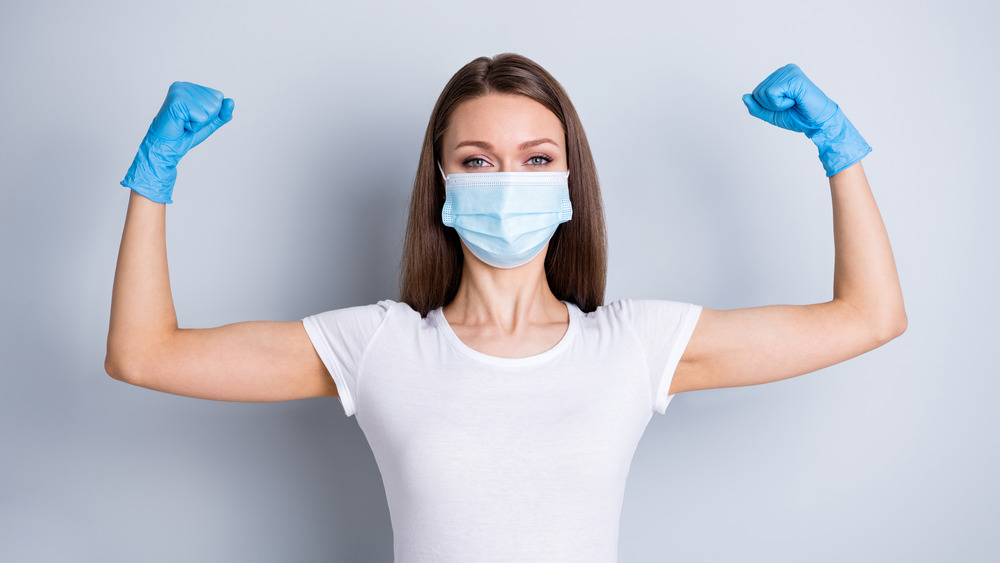 Woman in mask and gloves flexing arms