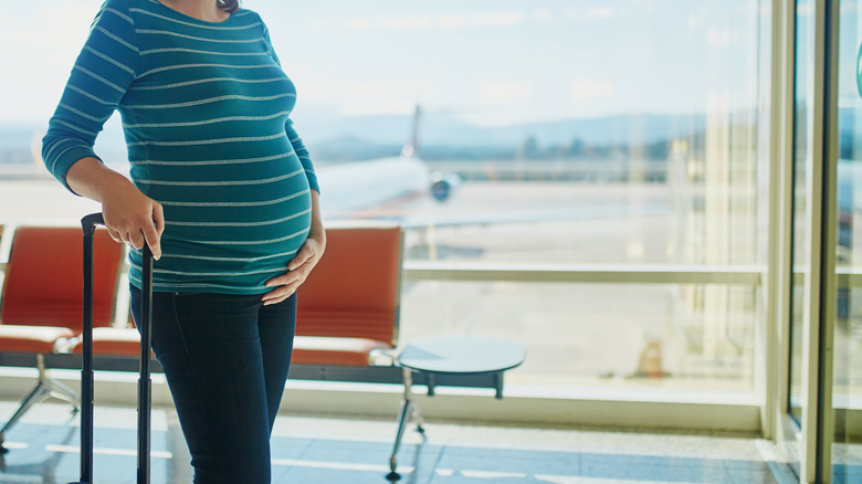 pregnant woman in a stripped T waiting to board her plane 