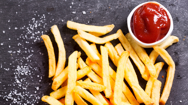 Pile of french fries with salt and ketchup