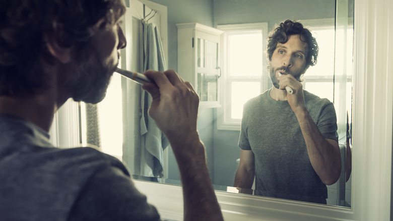 man brushing teeth in bathroom