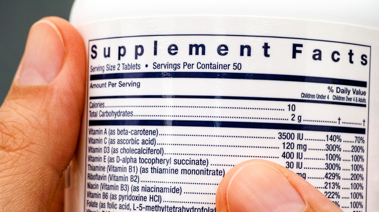 Man holding a bottle of multivitamins