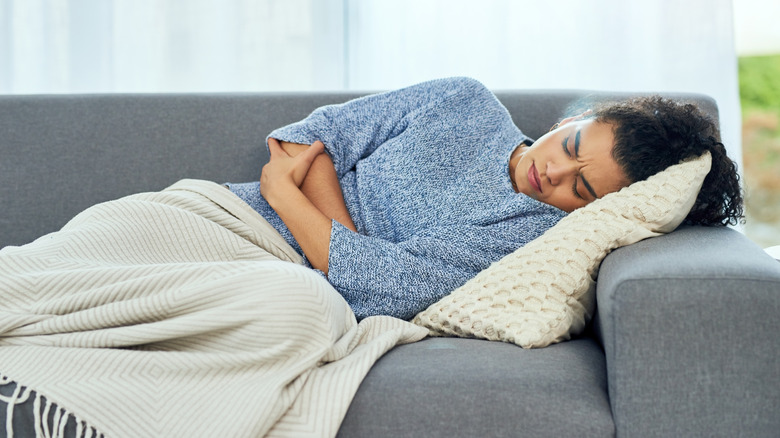 woman lying on the couch with a sick stomach