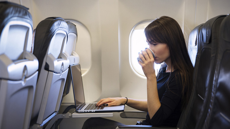 Woman drinking from a paper cup on a plane