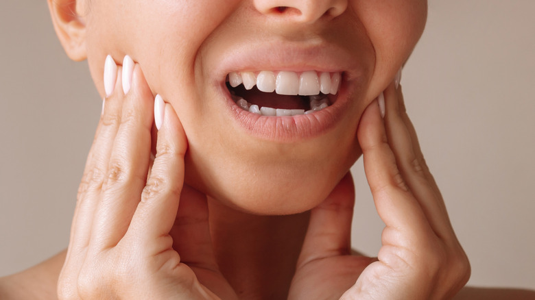 woman holding jaw in pain with both hands