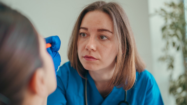 medical professional examining eye of female patient