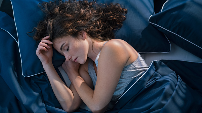 Woman sleeping in blue sheets