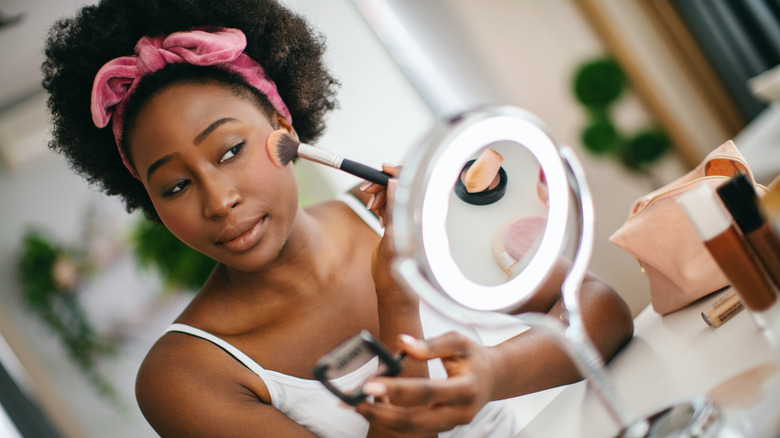 woman applying blush on her cheeks
