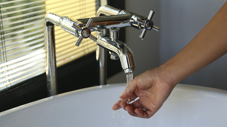 hand of woman with water coming out of faucet