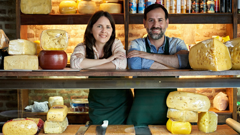 cheese store owners in front of an array of cheese