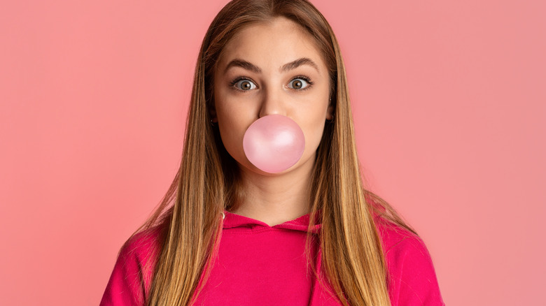 Woman blowing a pink bubble with gum 