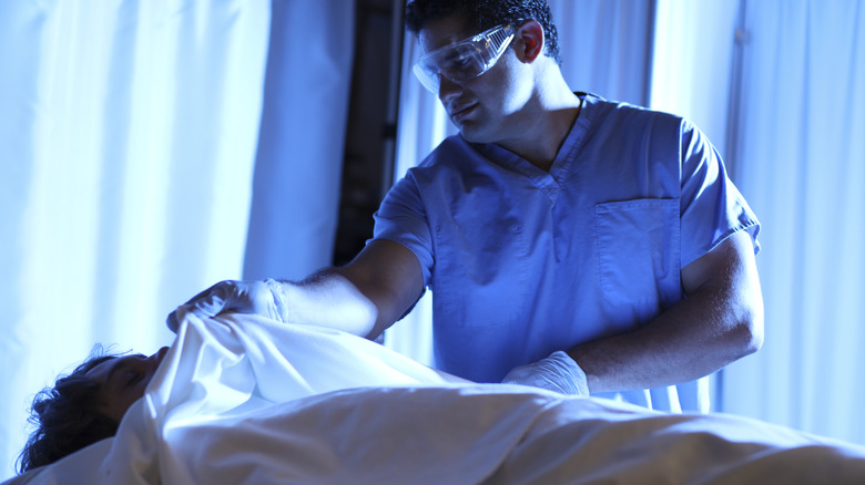 Mortician covering body with sheet