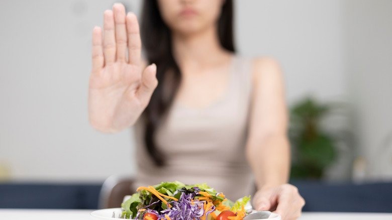 A woman pushing away a plate of salad