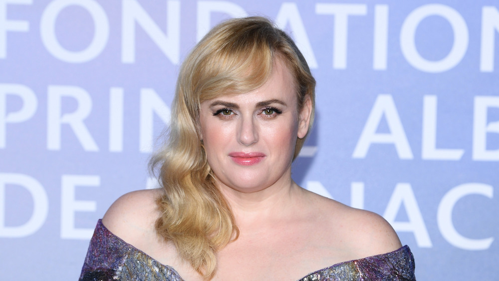 Rebel Wilson grinning in an off the shoulder gown 