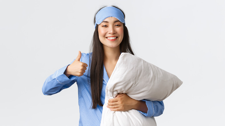 woman holding pillow and wearing eye mask