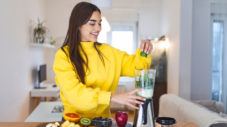 A woman makes a smoothie at home