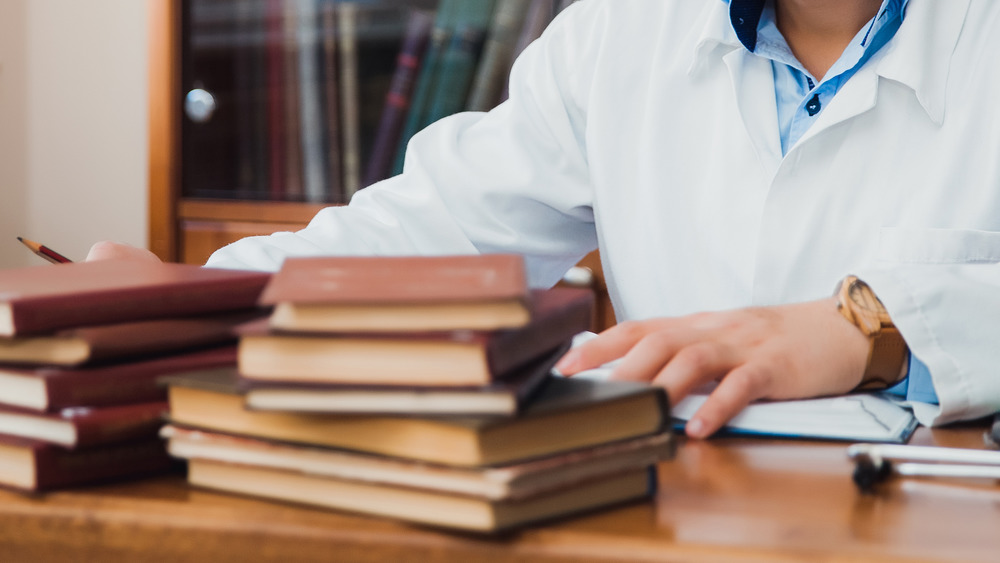 Medical student with stacks of books