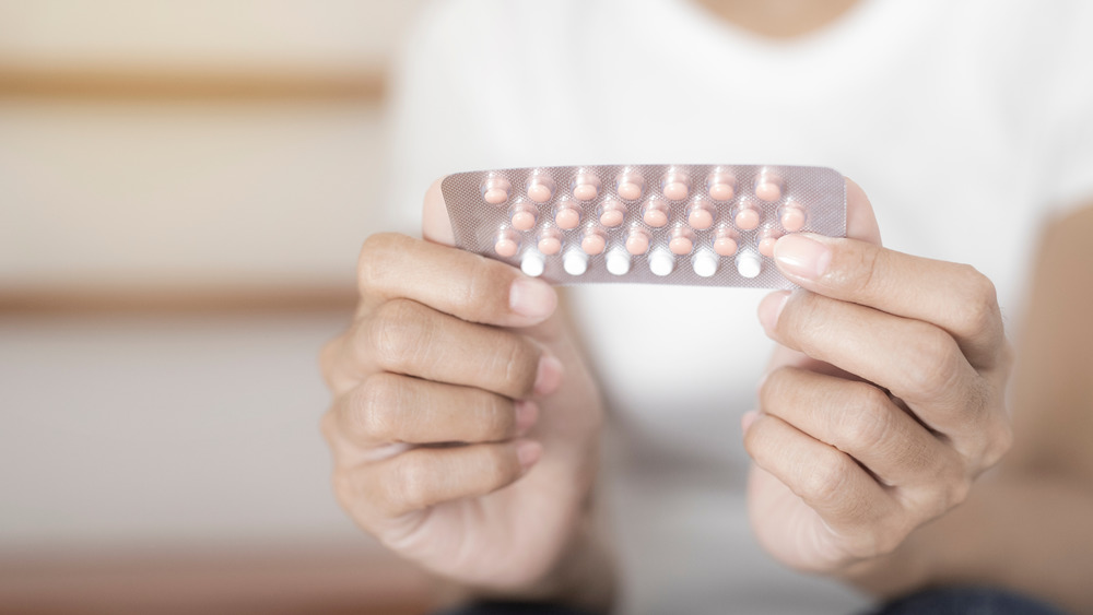 Closeup of a woman holding birth control pills