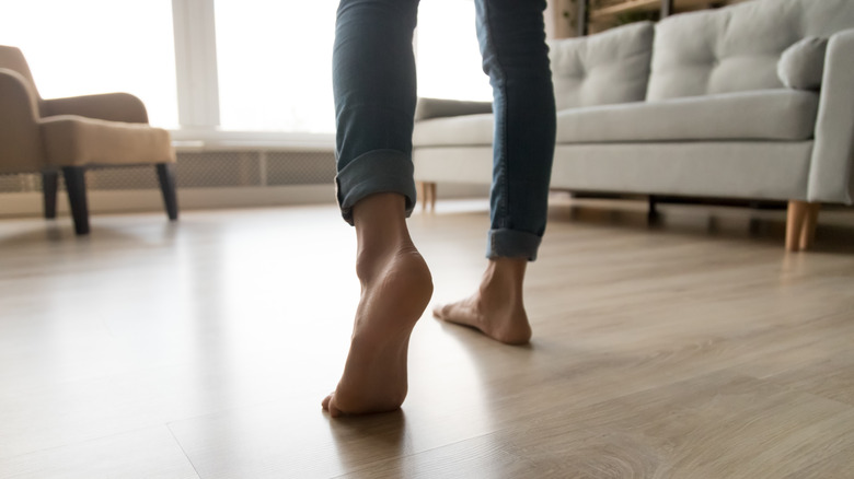 Close-up of a person's feet as they walk across their living room floor