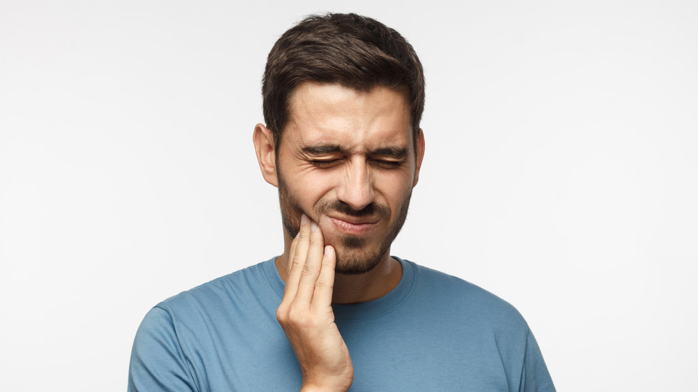 Man holding the side of his mouth