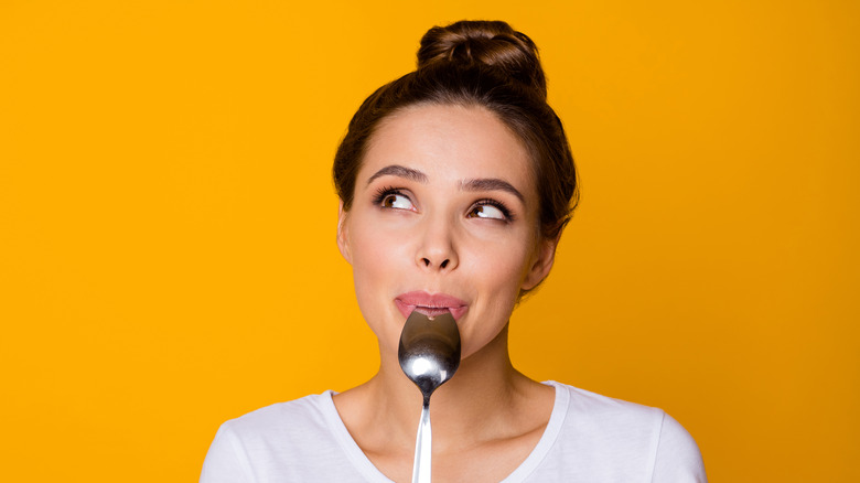 Girl holding spoon and thinking about breakfast