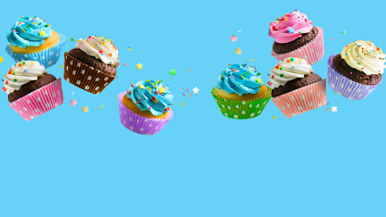 Eight cupcakes up in the air surrounded by sprinkles