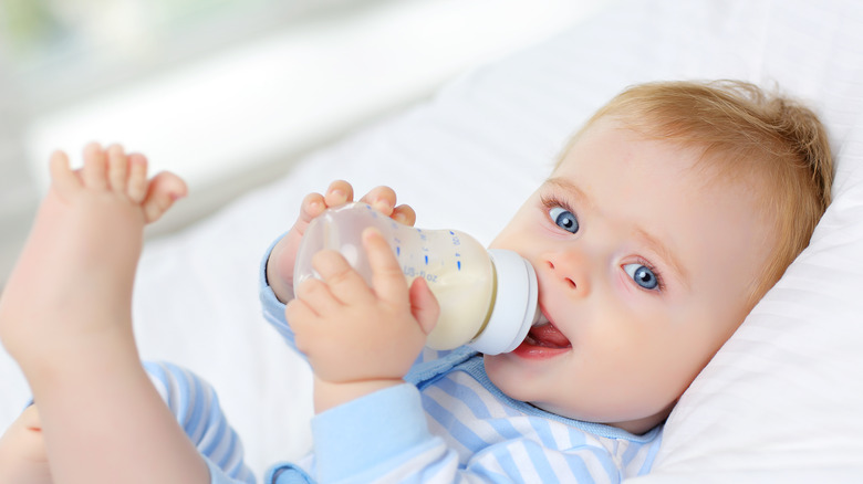 Baby lying down drinking from a bottle