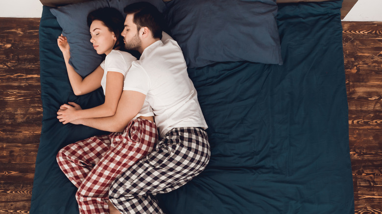 A spooning couple asleep in bed 