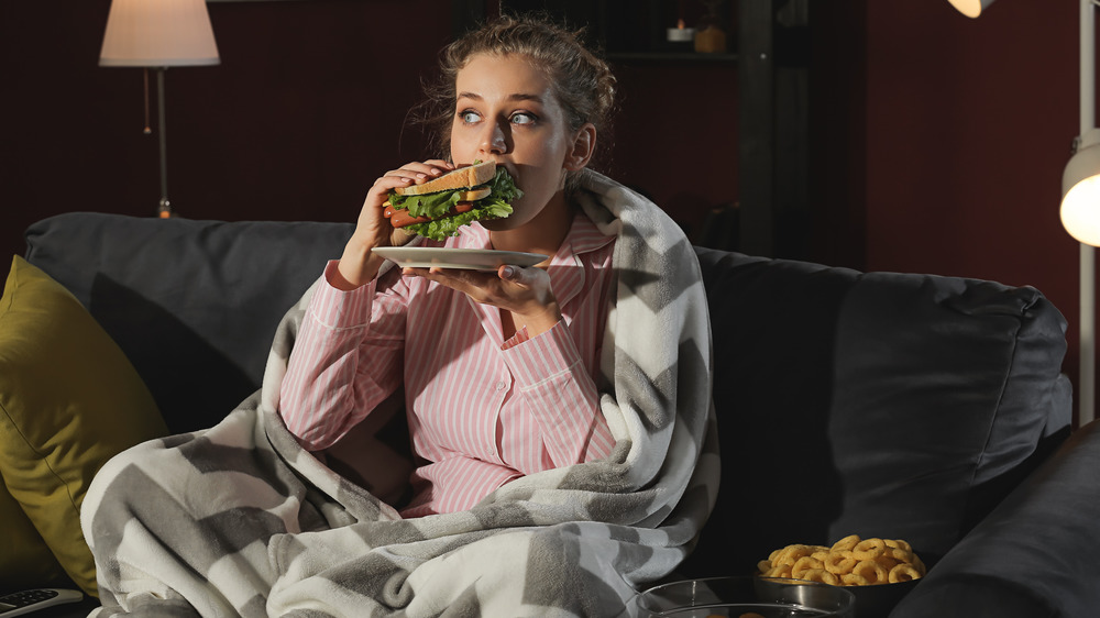 woman eating junk food at night