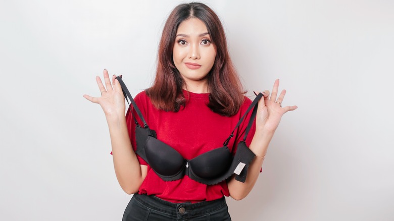 woman holding a bra and looking skeptical