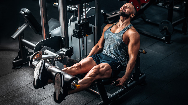 muscular man on leg machine in gym