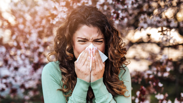 woman sneezing in a park