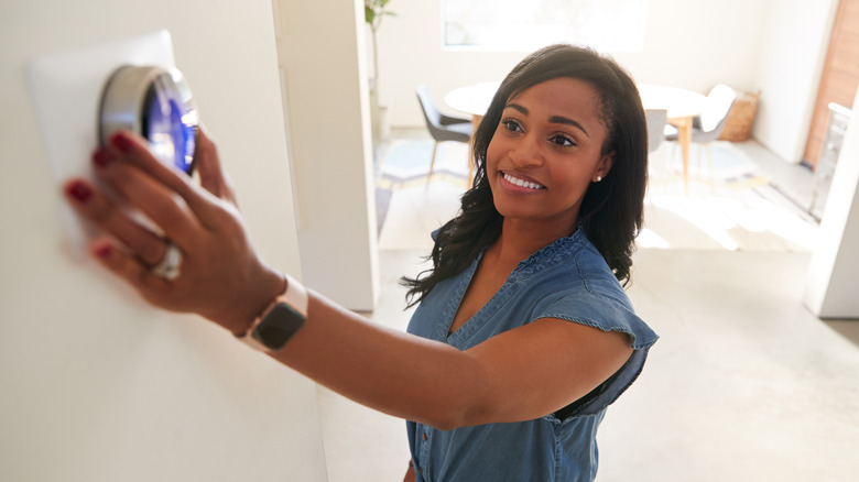 woman adjusting thermostat