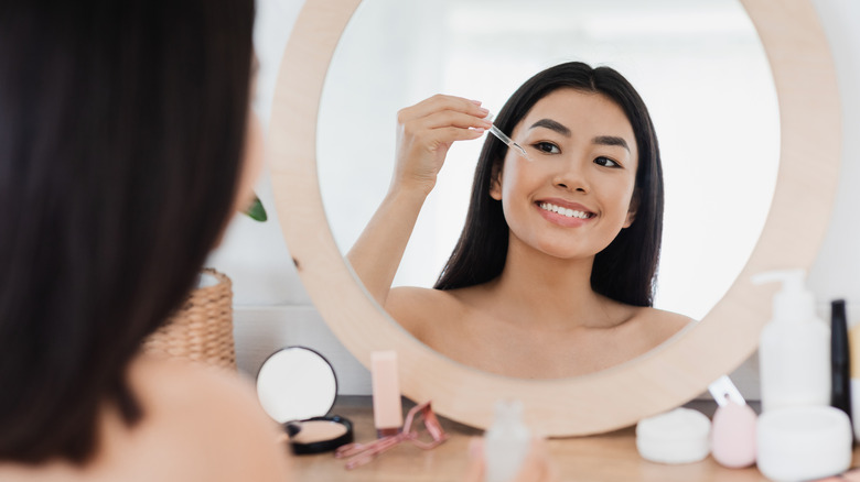 A woman is applying a vitamin c serum to her face