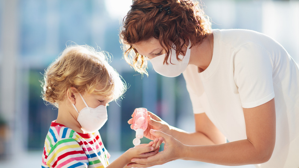 Mother squeezing hand sanitizer into child's palm