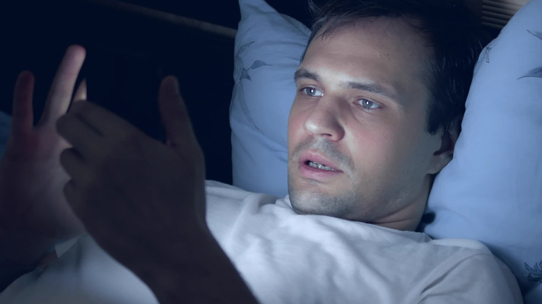 man reading from his cell phone in bed