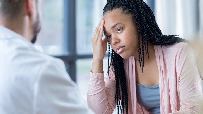 young woman describing her headache while talking with doctor