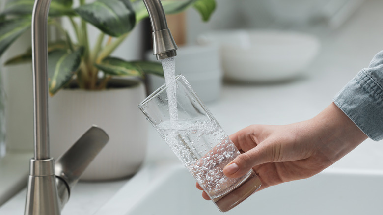 Hand filling up glass of tap water