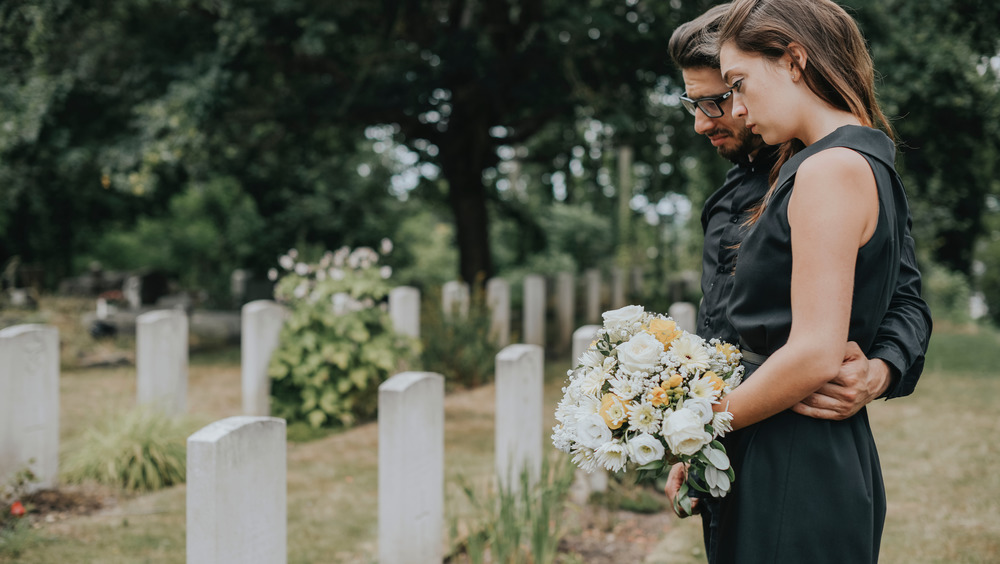 couple standing at gravesite