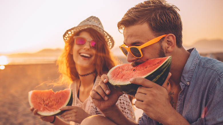 couple eating large wedges of watermelon