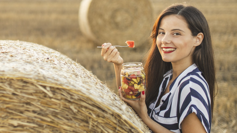 woman eating a bowl of fruit at a farm field