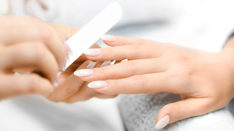 Woman having nails filed at salon