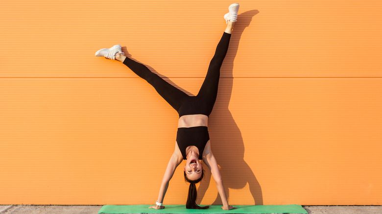 Woman doing handstand on wall