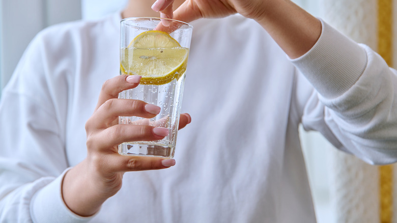 hand squeezing lemon into water glass