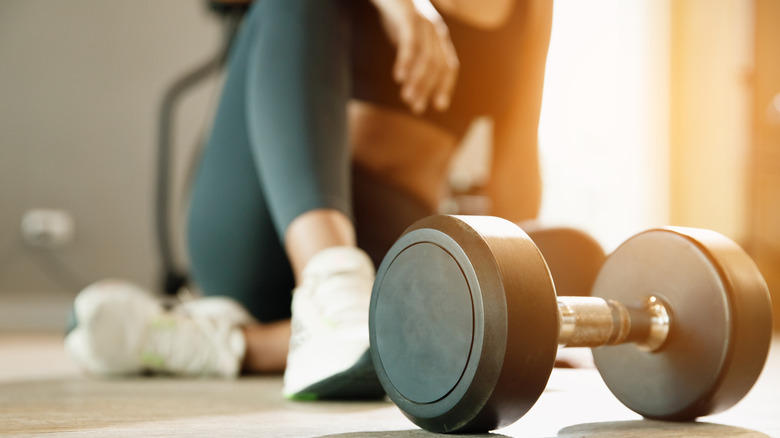 woman silhouetted behind free weights