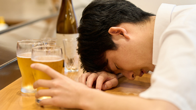 drunk man surrounding by glasses of beer