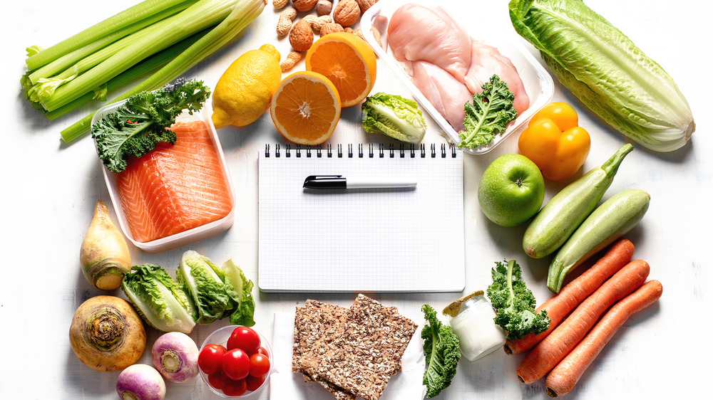 Healthy food scattered around a notepad
