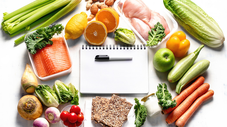 Healthy food scattered around a notepad