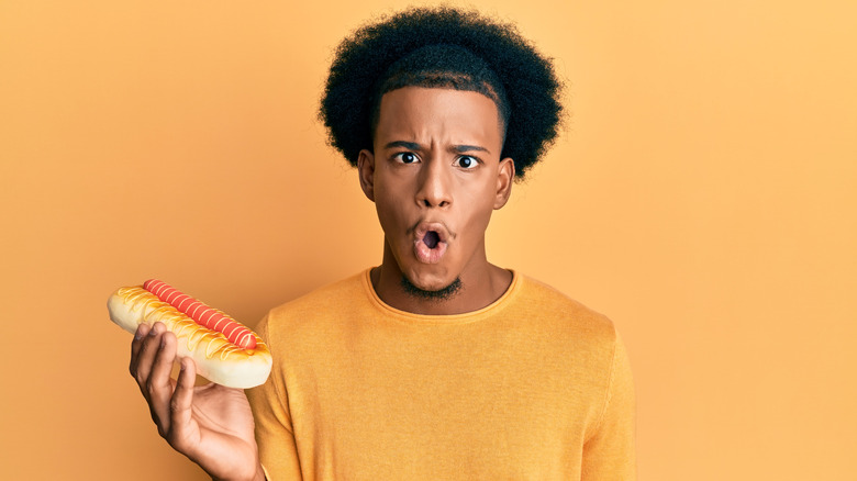 surprised man holding hot dog