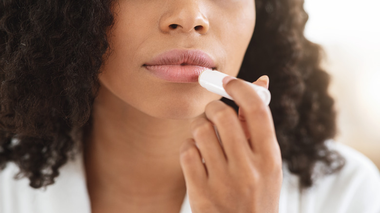 Woman putting on lip balm