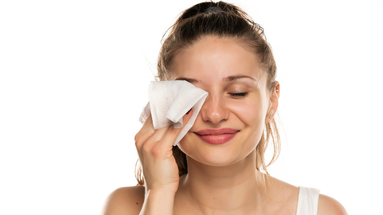 smiling woman removing eye makeup with a wipe